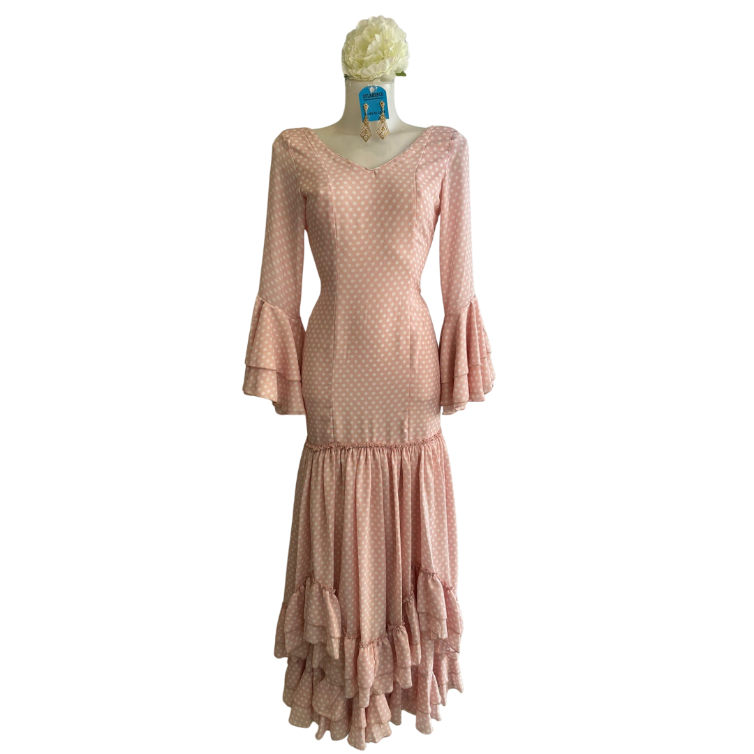 Vestido de flamenca rosa con lunares, diseño tradicional con vuelo y confección artesanal.